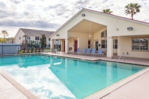 A swimming pool with lounge chairs and a covered area with doors. - Celebrate at Club Cortile (Kissimmee)