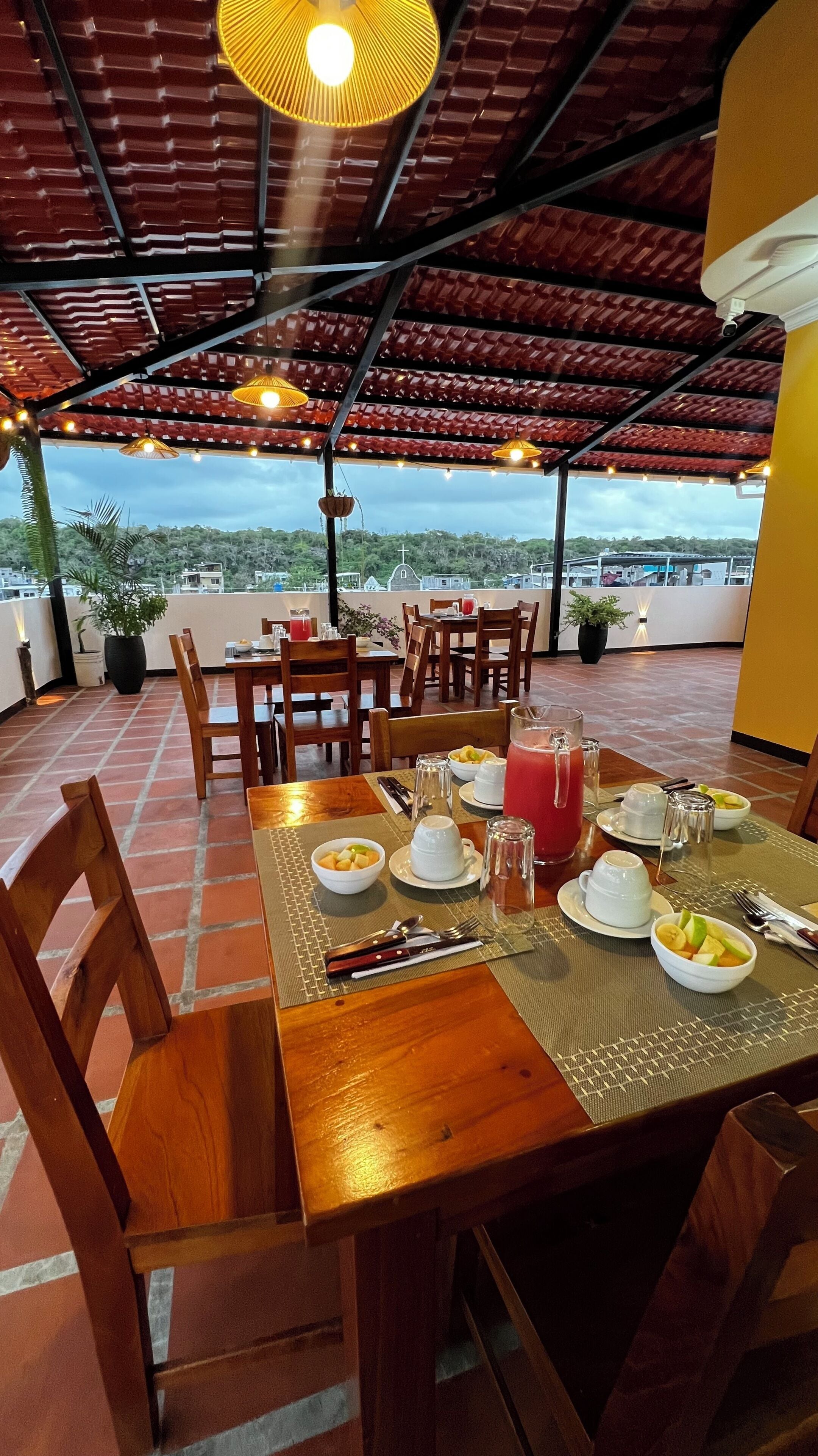 A dining area with a table set for two, a pitcher of red drink, and a view of the landscape.