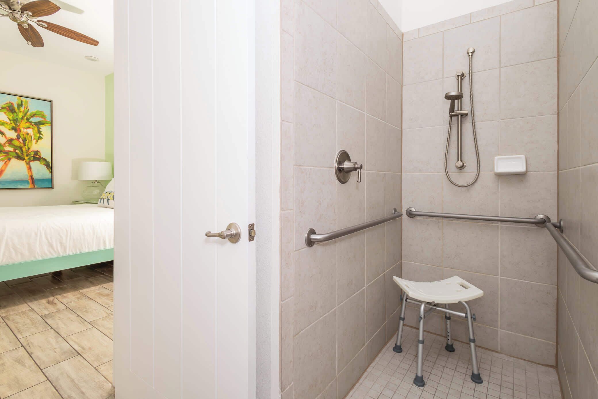 Ein Badezimmer mit Dusche, Haltegriffen und einer rollstuhlgerechten Sitzbank.