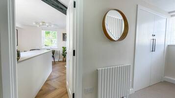 A hallway with a white radiator, a round mirror on the wall, and a white door.