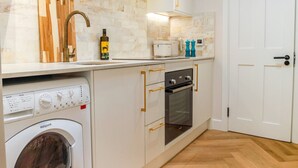 Una cucina moderna con lavatrice integrata, forno a microonde e piano cottura.