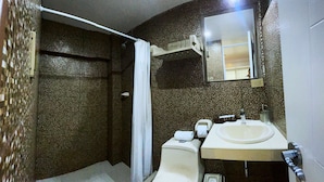 Une salle de bain équipée d’une douche, de toilettes, d’un lavabo et d’un miroir.