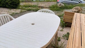Ein Tisch mit Stühlen in einem Garten mit Blick auf einen See und Hügel.