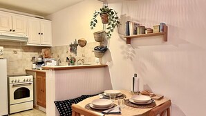 Eine kompakte Küche mit weißen Schränken, einem Herd und einem Essbereich mit Holztisch und Stühlen.