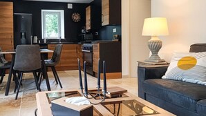 Een moderne woonkamer met een bank, een salontafel en een eethoek met stoelen en een tafel.