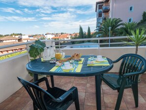A round table with chairs on a terrace, breakfast items, and a view of buildings.