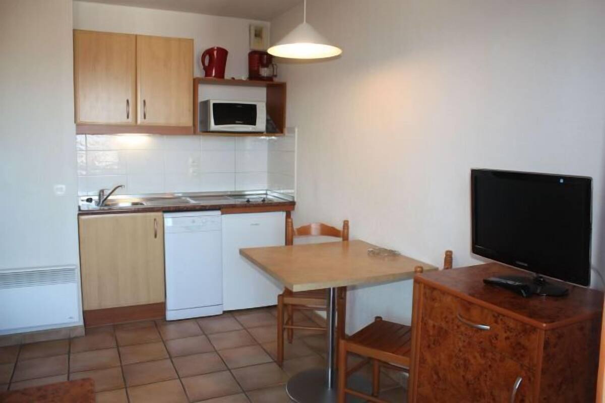 Una cocina pequeña con microondas, pileta y una mesa con sillas.