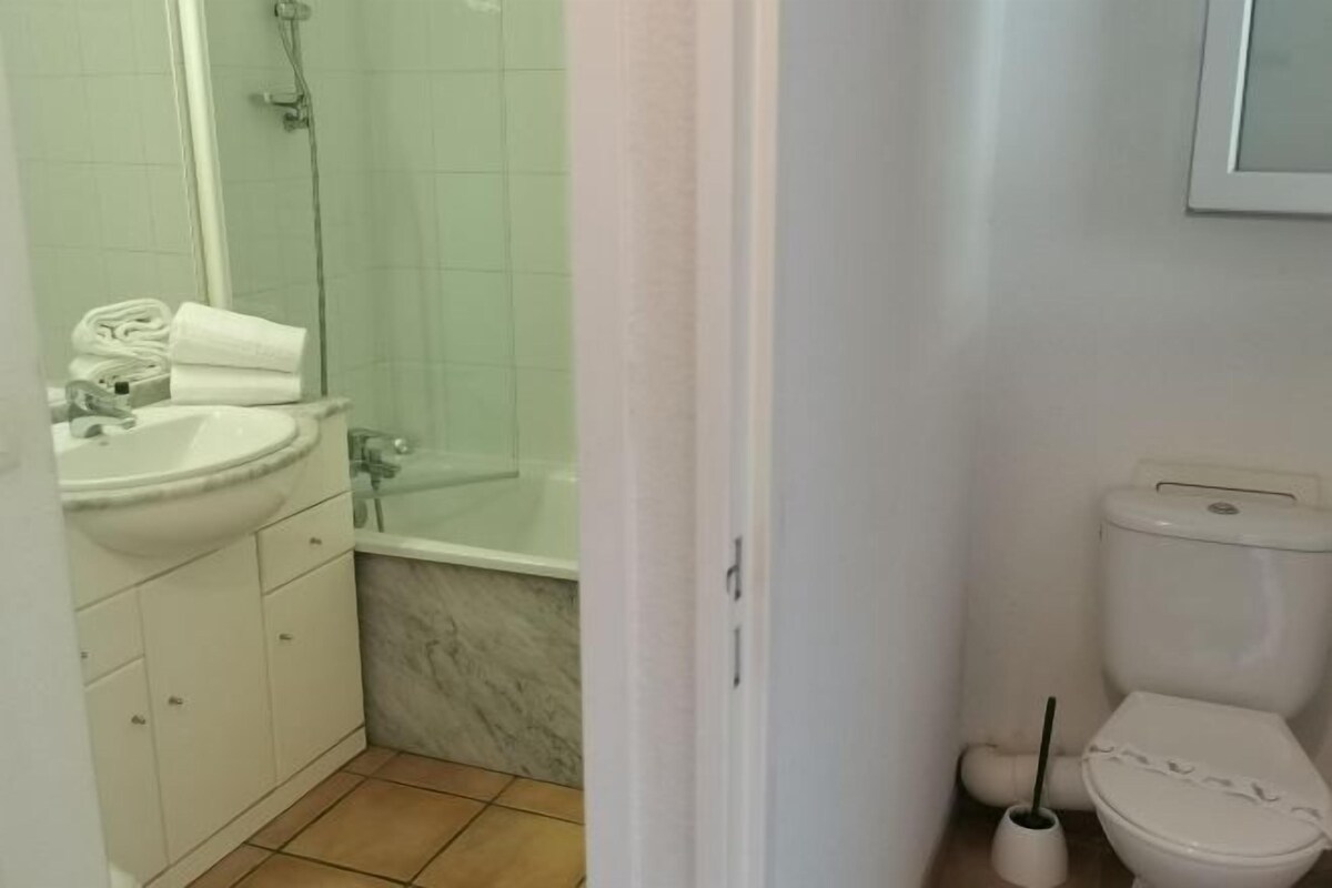 A bathroom with a sink, mirror, shower, and toilet.