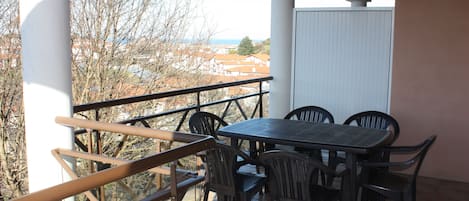 A balcony with a table and chairs, overlooking a residential area.