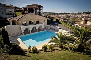 A residential property with a swimming pool, a covered patio, and a view of the surrounding neighborhood.