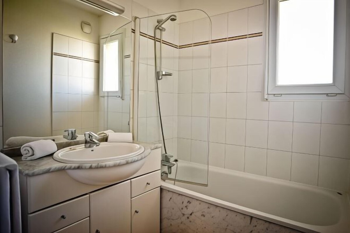 A bathroom with a sink, mirror, and shower.