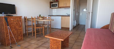 Un espacio habitable compacto con kitchenette, comedor y zona de estar.