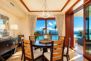 A dining area with a table, chairs, and a view of the ocean.
