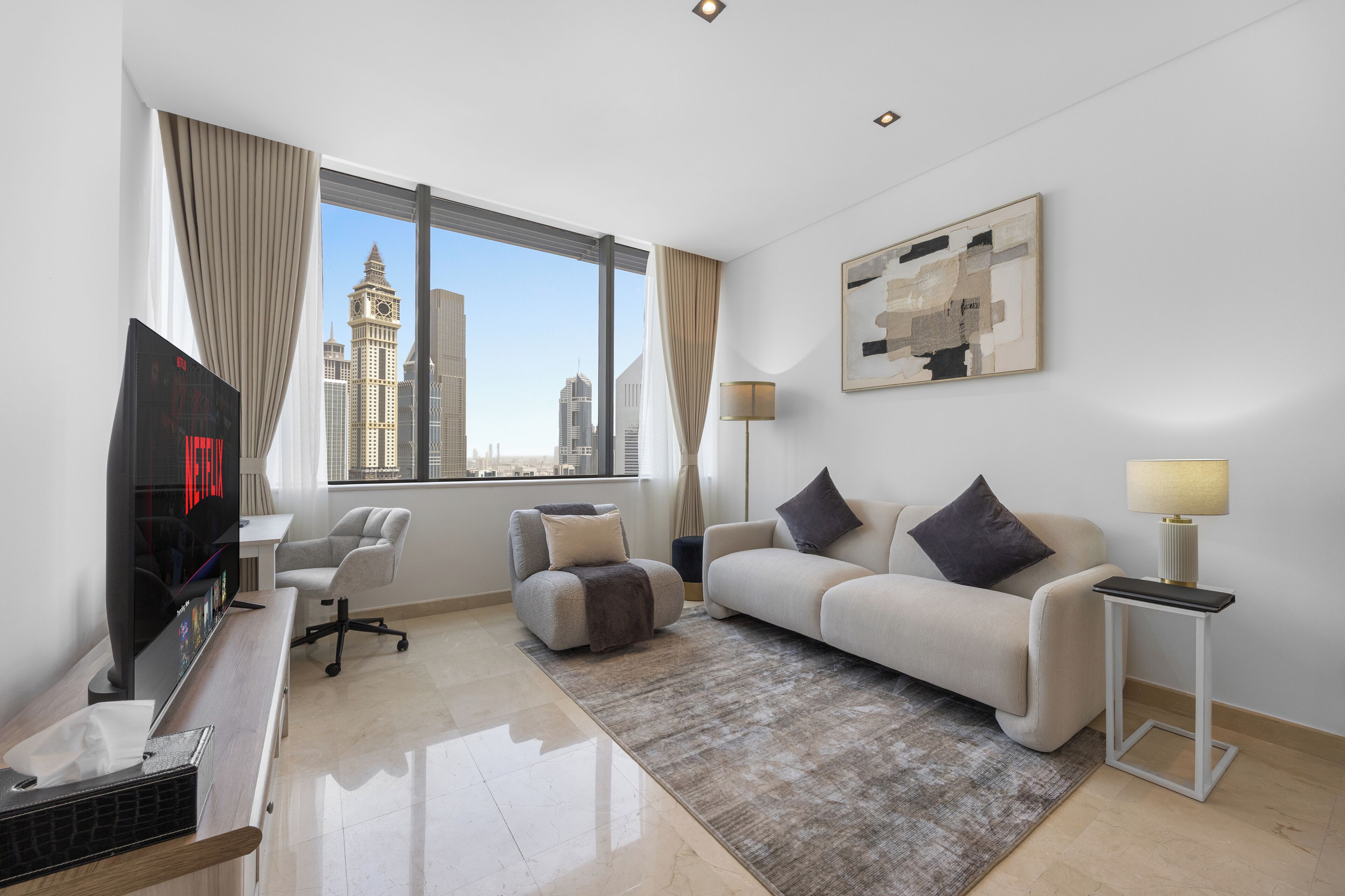 Quarto de hotel moderno com uma janela grande, televisão de tela plana, sofá, escrivaninha e luminária.