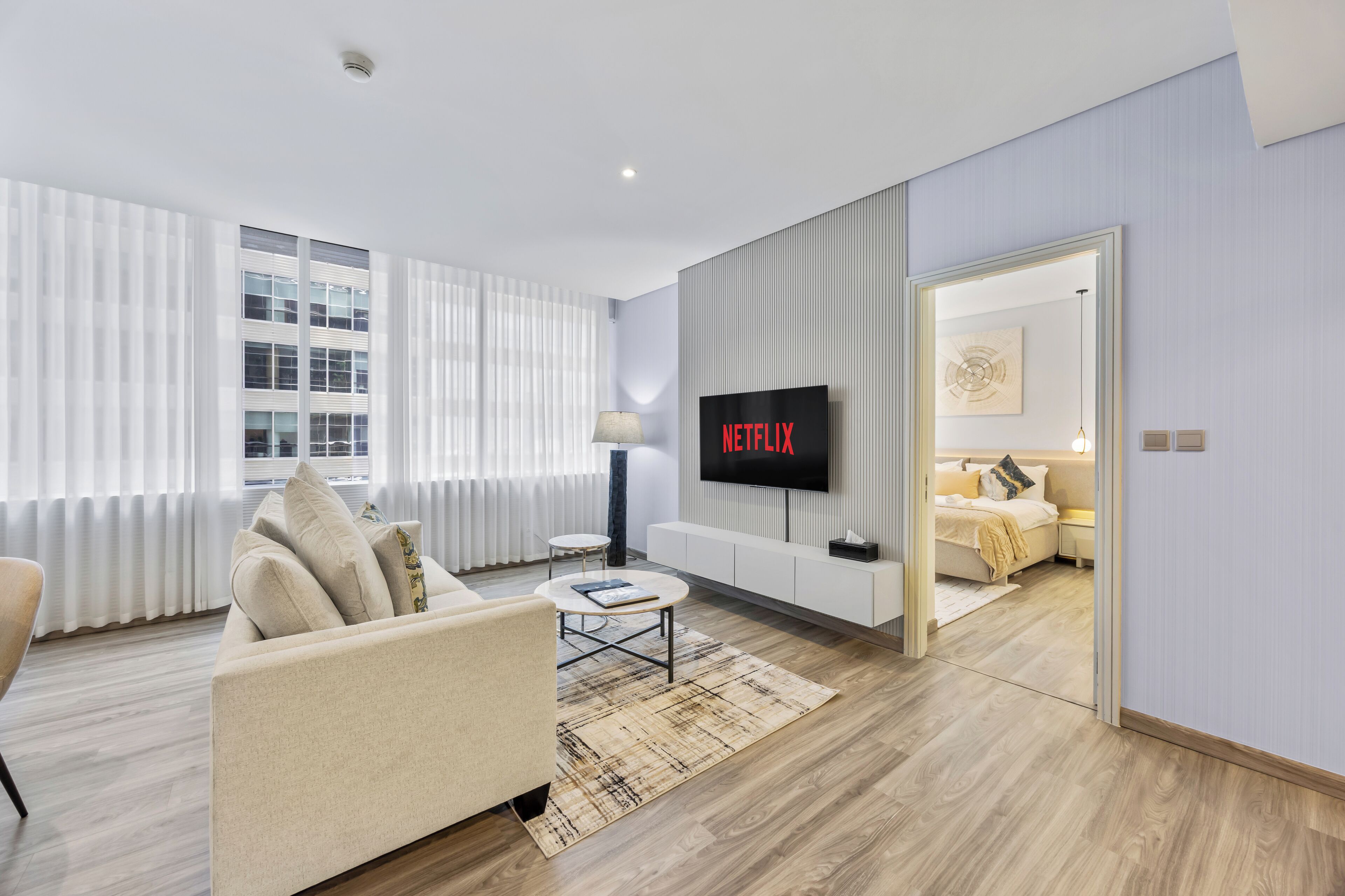 Una sala de estar moderna con un sofá, una mesa de centro y un televisor mostrando 'NETFLIX'.