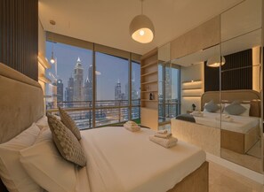 Une chambre moderne avec un grand lit, une vue sur la ville et une armoire avec des portes miroir.