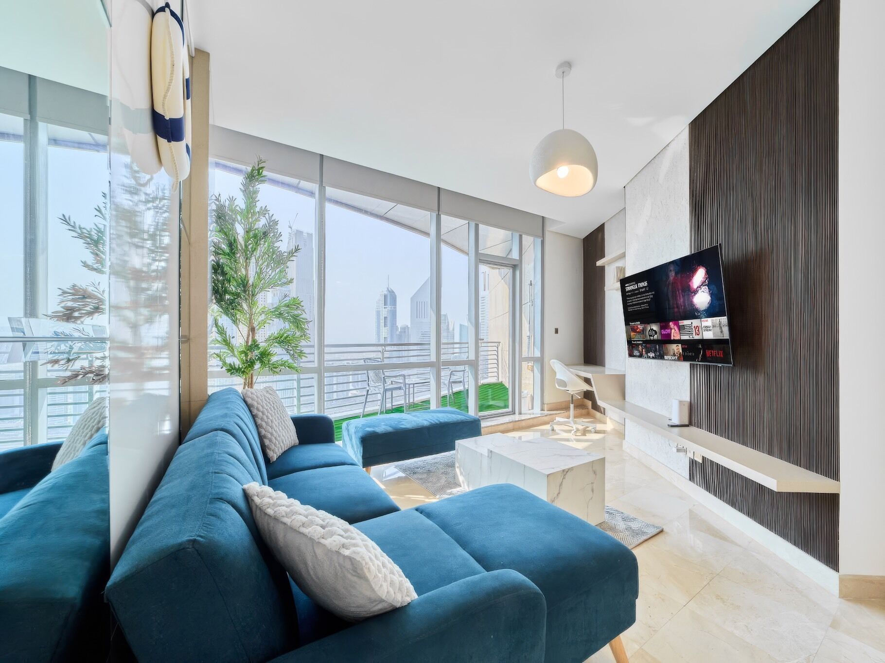 A modern living room with a large sofa, a coffee table, and a TV mounted on the wall.