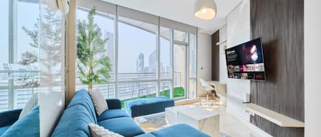 A modern living room with a large sofa, a coffee table, and a TV mounted on the wall.