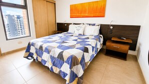 A bedroom with a bed, a nightstand, a wall-mounted lamp, and a window with a view of buildings. - Laureles Deluxe Apartment  Medellin  (Medellín)