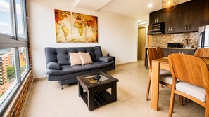 A modern living room with a sofa, coffee table, and dining area. - Laureles Deluxe Apartment  Medellin  (Medellín)