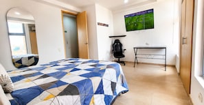 A hotel room with a bed, a desk, a chair, a TV, and a mirror. - Laureles Deluxe Apartment  Medellin  (Medellín)