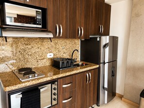 A kitchen with a microwave, stove, sink, and stainless steel refrigerator. - Laureles Deluxe Apartment  Medellin  (Medellín)