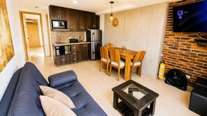 A modern living room with a sofa, a coffee table, and a dining area with chairs. - Laureles Deluxe Apartment  Medellin  (Medellín)