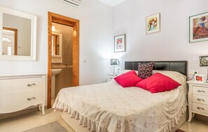 Een slaapkamer met een bed, nachtkastjes, een kaptafel, een spiegel en kunstwerken aan de wanden.