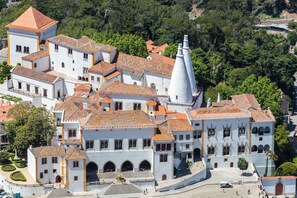 A historic building with multiple white facades, red-tiled roofs, and a prominent white tower.