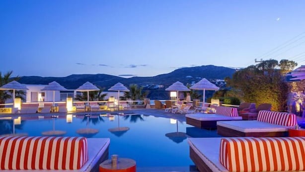 Un espace piscine doté de chaises longues et de parasols, entouré de montagnes.