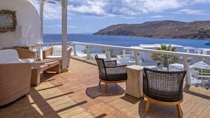 Un espace extérieur ensoleillé, aménagé avec des meubles en osier et offrant une vue sur la mer.