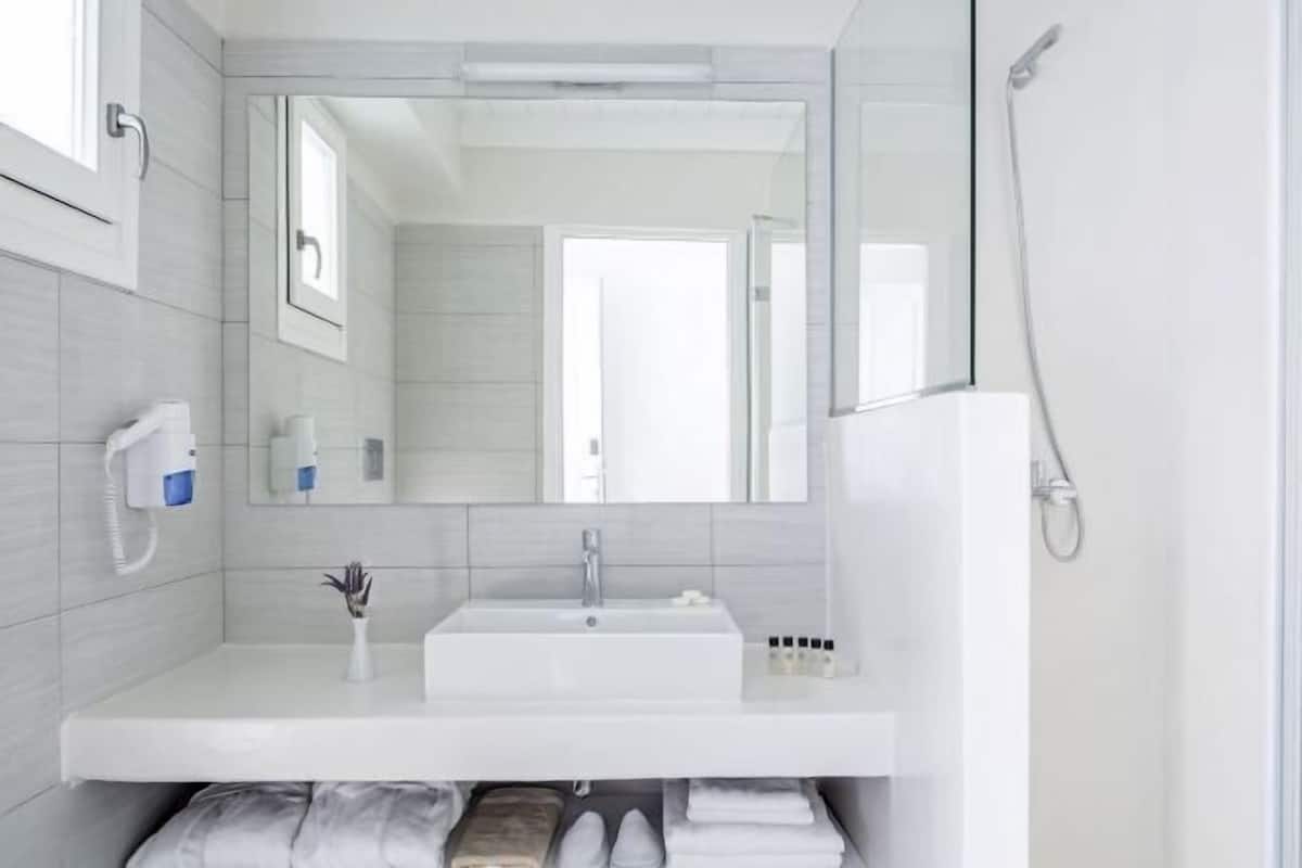 Une salle de bain moderne avec un lavabo blanc, un miroir et une douche.