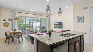 A modern kitchen with a granite countertop, stainless steel appliances, and pendant lighting. - Dream Days At Enclaves (Davenport)