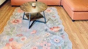 Una habitación con sofá modular, una mesa de centro redonda, alfombra floral y dos lámparas de pared.