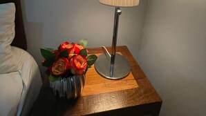 Et natbord med en lampe og en vase med kunstige blomster.