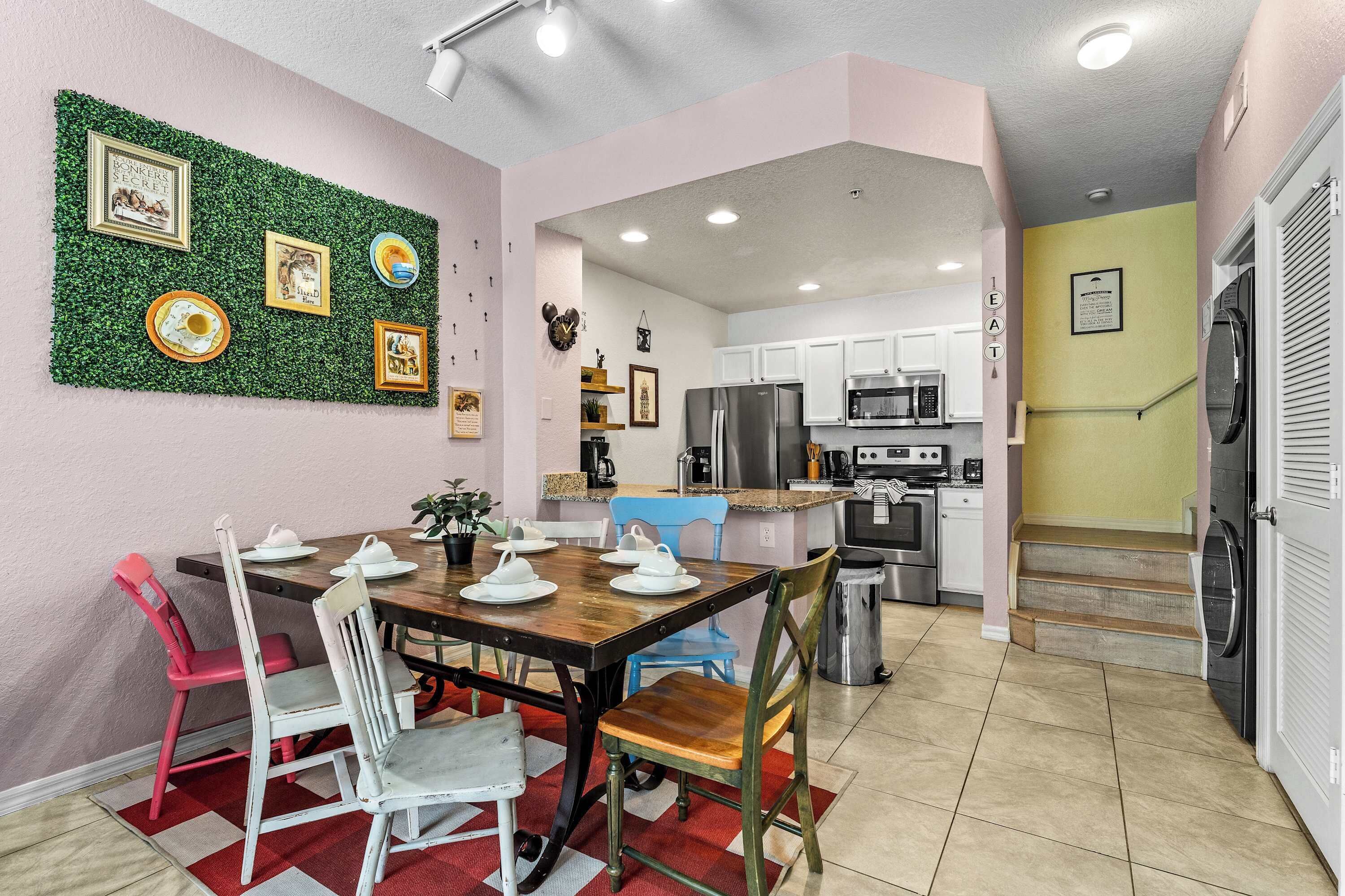 A modern kitchen with white cabinets, stainless steel appliances, and a dining area with a wooden table and chairs.