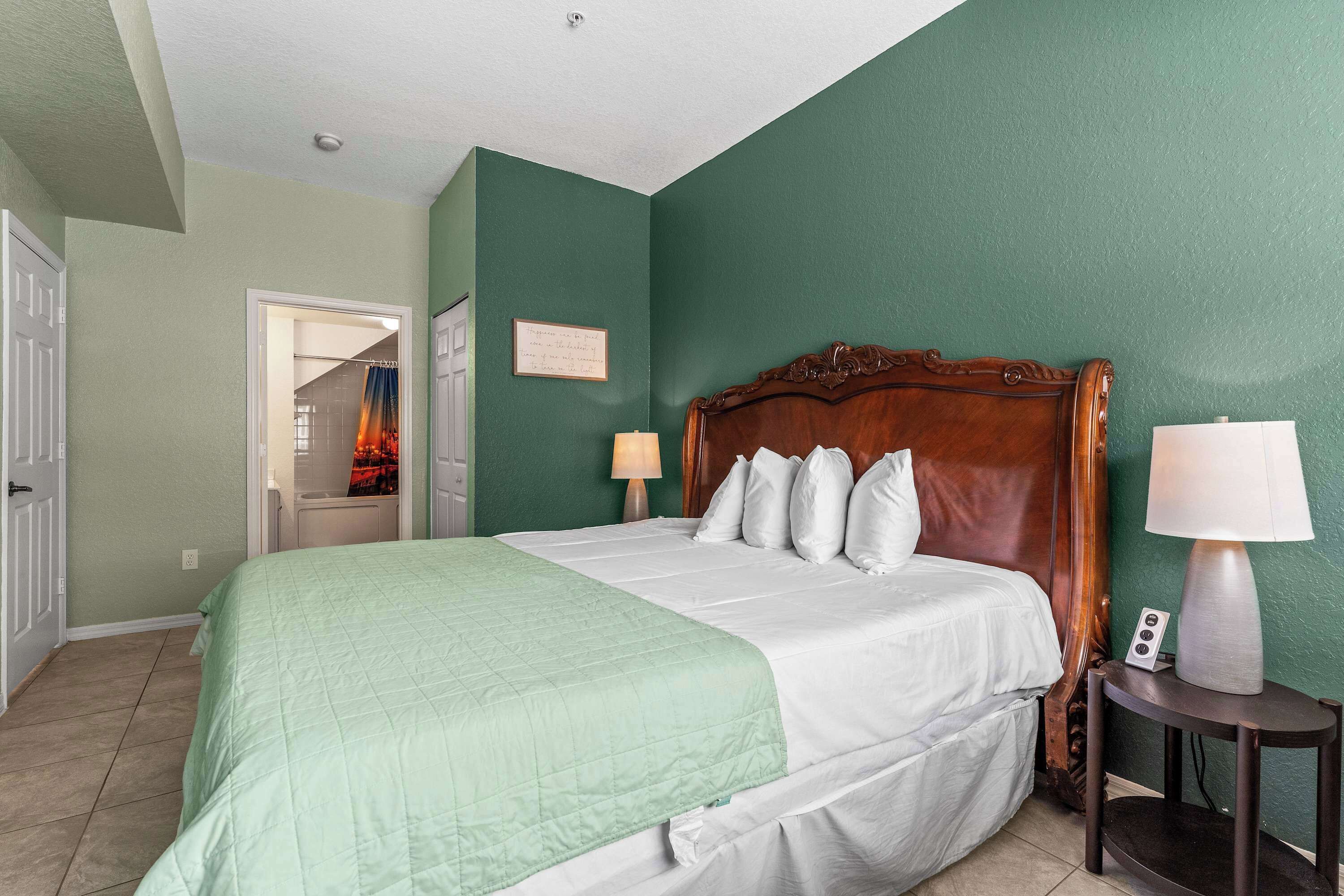 A bedroom with a large bed, two bedside lamps, and a wooden headboard.