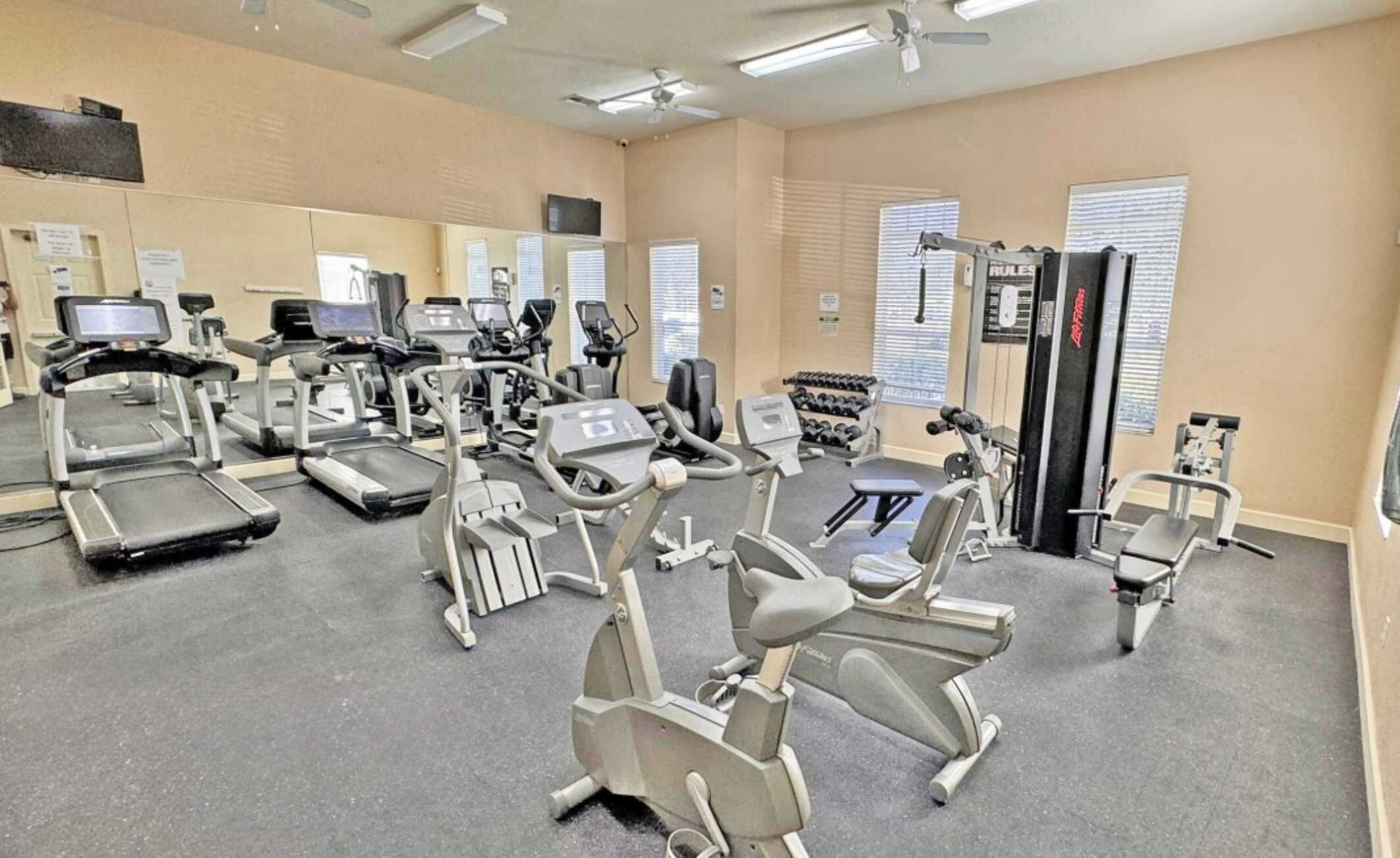 A gym with treadmills, elliptical machines, and free weights.