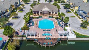 A resort with a central swimming pool, a dock, and a building with a symmetrical facade. - Enchanted At 7 Dwarfs Lane (Kissimmee)
