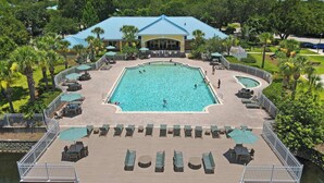 A large pool surrounded by lounge chairs and umbrellas, with a deck extending over water. - Family Friendly Relax Villa (Kissimmee)