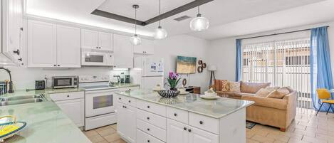 A modern kitchen with white cabinets, a central island, and pendant lighting.