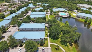 An aerial view of a residential area with multiple buildings, a swimming pool, and a lake. - Family Friendly Relax Villa (Kissimmee)
