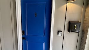 Een blauwe deur met het nummer 9, een brievenbus en een deurmat bij de ingang.