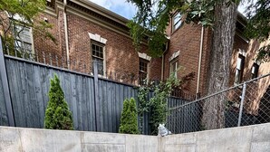 A backyard with artificial grass, a concrete wall, and a wooden fence.