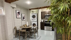 Cocina compacta con comedor, lavadora y una planta grande en maceta.