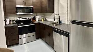 Una cocina moderna con electrodomésticos de acero inoxidable, armarios de madera y un salpicadero de azulejos blancos.