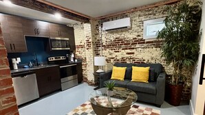 Ein gemütlicher Wohnbereich mit einer Küche, einem Sofa mit gelben Kissen und einem Couchtisch.