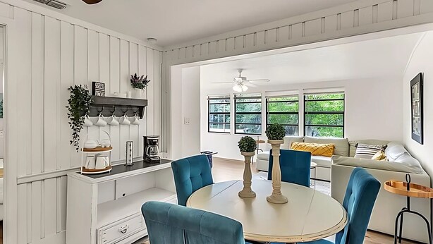 Una cocina moderna con armarios blancos, una mesa de comedor con sillas azules y un sofá con cojines amarillos.