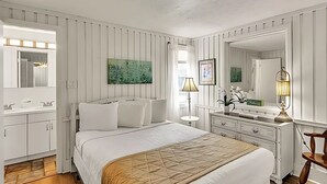 Un dormitorio con cama, cómoda, espejo y obras de arte en la pared.
