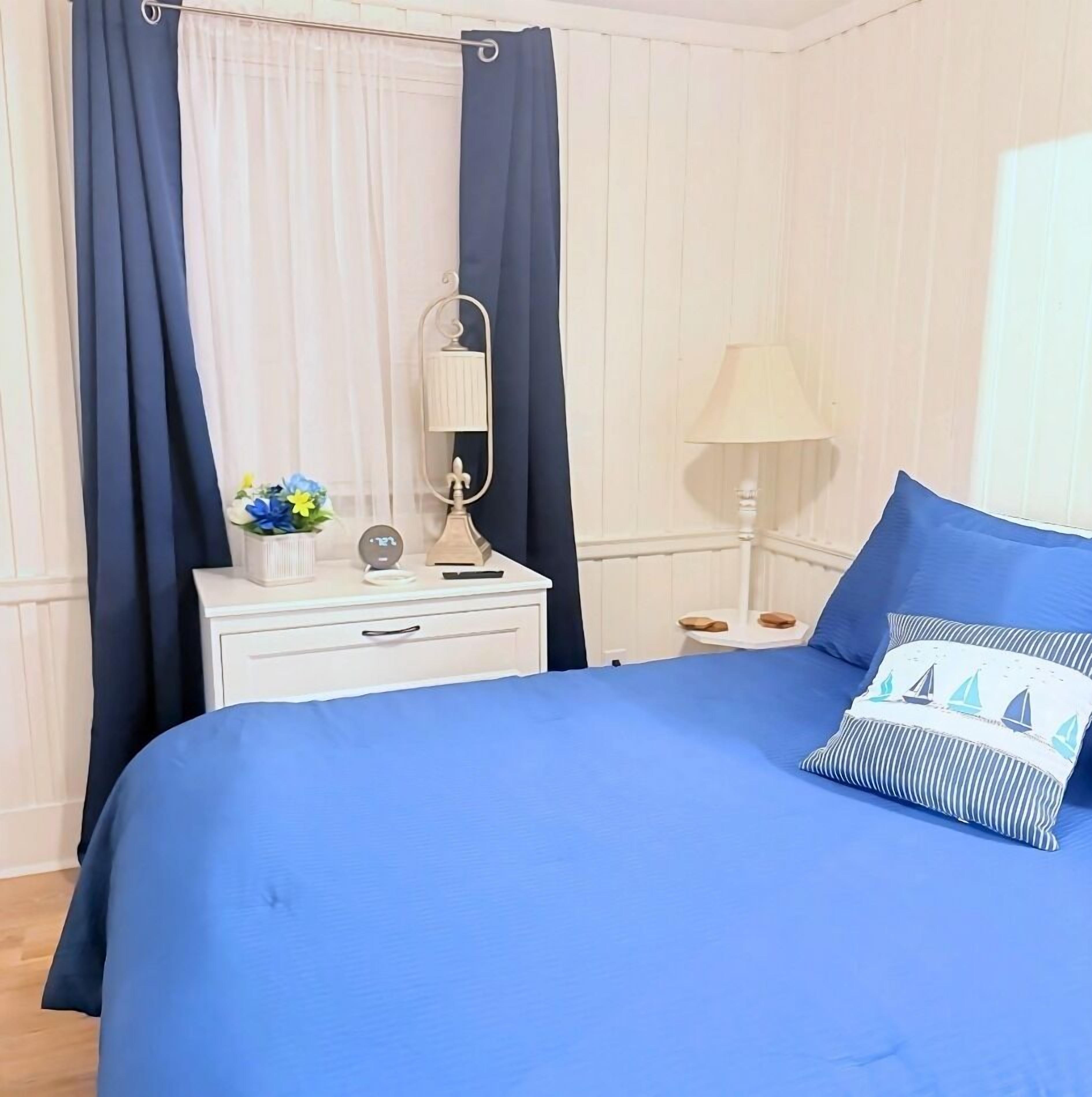 A bedroom with a bed, a nightstand, a lamp, and curtains.